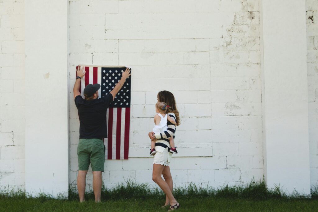 Family celebrating with American flag outdoors, symbolizing patriotism and togetherness.